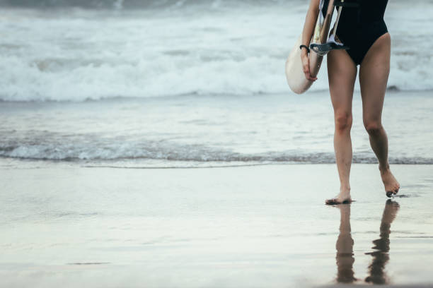 Young woman is walking on Canggu beach after surfing ocean.Canggu beach - Bali Island.