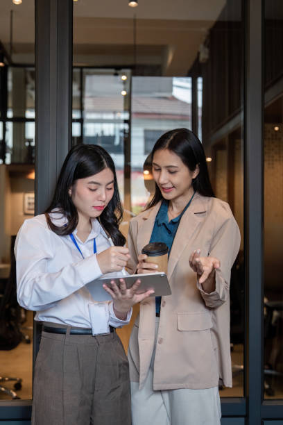 istock Collaborative women discussing project details while reviewing data on digital tablet in modern office 2194303906