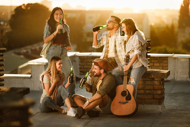 istock Happy friends drinking beer on a rooftop at sunset. 2194318760