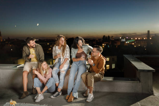 istock Cheerful friends drinking wine during party night on a roof. 2194319207
