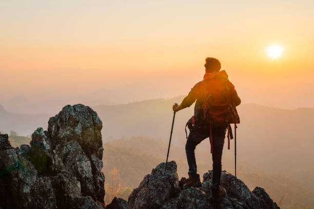 istock man is standing on a mountain top with a backpack and a pair of poles 2194319255
