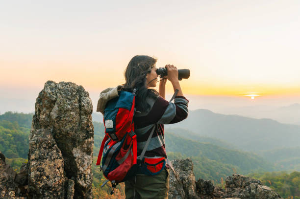 istock woman is standing on a mountain top, looking through a binoculars 2194319263