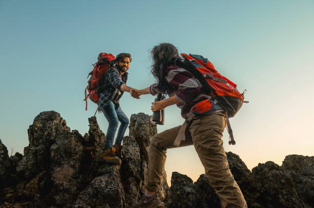 istock man and a woman are helping each other climb a mountain 2194319267