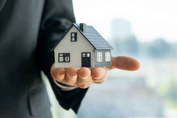 istock Real estate agent holding a miniature house in open hand 2194319383
