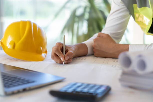 istock Architect reviewing plans on desk with laptop and calculator 2194319419