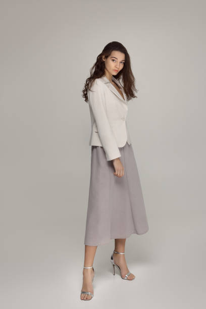 istock Elegant Woman In White Blazer And Midi Skirt Posing In Minimal Studio Setting 2194319922