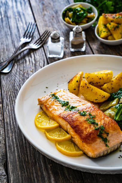 istock Fried salmon, fried potatatoes with stir-fried bok choy on wooden table 2194322853