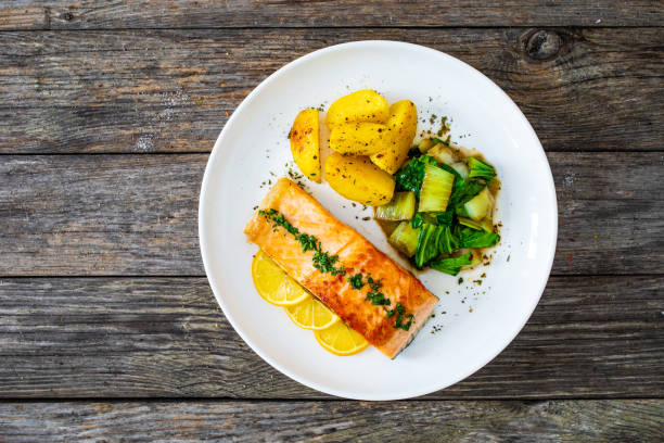 istock Fried salmon, fried potatatoes with stir-fried bok choy on wooden table 2194322874