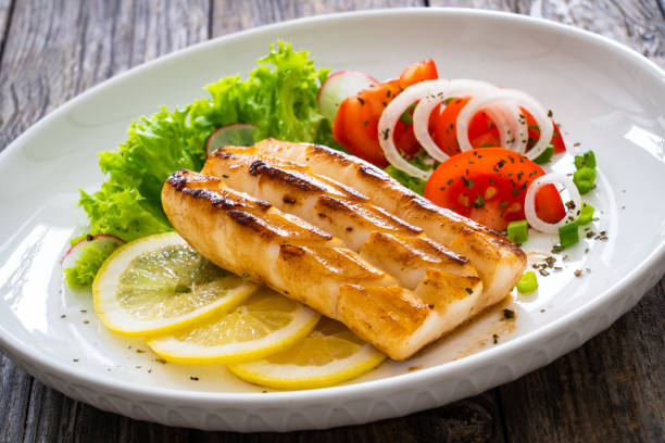 istock Fried calamari steak with lemon and fresh vegetables on wooden table 2194323186