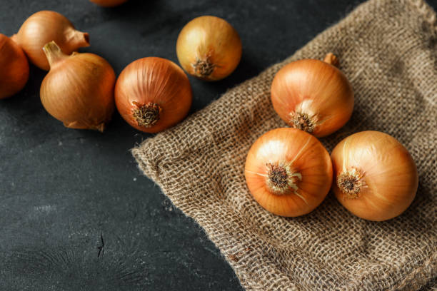 istock Fresh yellow onions placed on a rustic burlap fabric, showcasing their natural texture. Ideal for culinary themes, organic food concepts, or traditional kitchen settings 2194325609