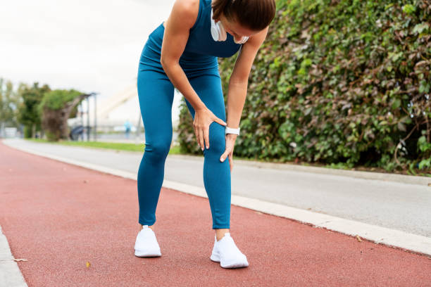 istock Female runner experiencing leg trauma while running on run track outdoors on city street. 2194326057