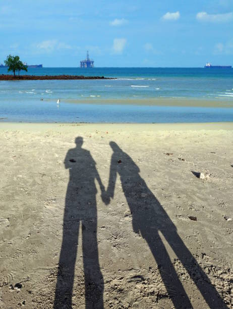 couple shadows holding hands at sandy beach