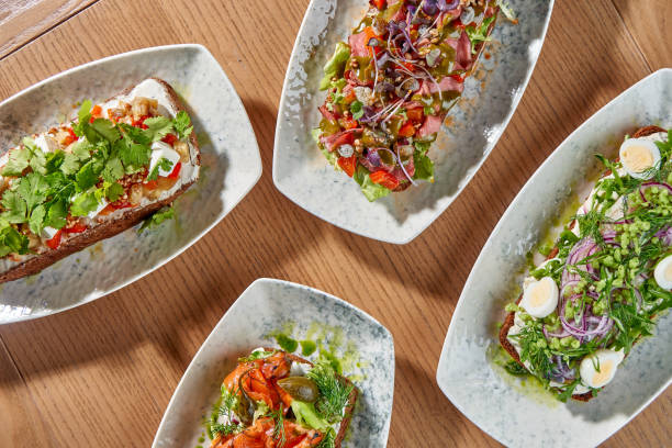istock A delectable spread of four open-faced sandwiches, or smorrebrod, each with a unique and vibrant combination of toppings. 2194330752