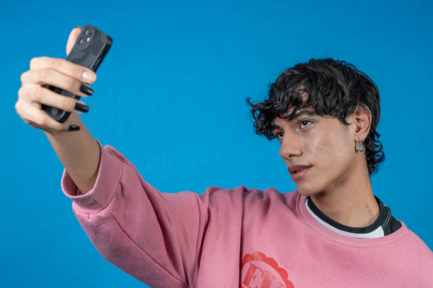 istock Young man taking a selfie with smartphone on blue background 2194339957