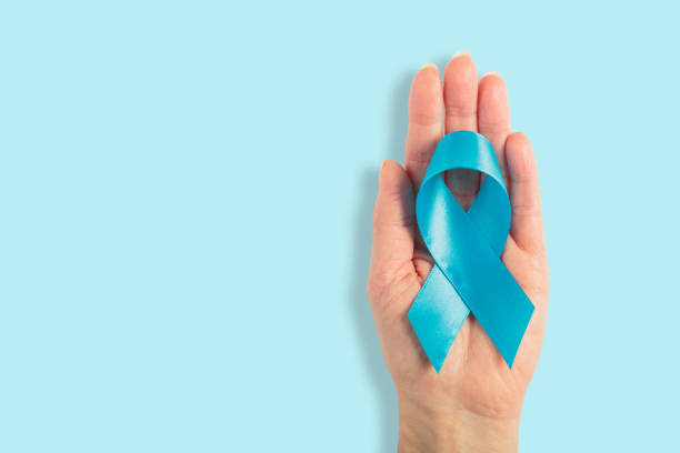istock Blue cancer ribbon in woman's hand on white background 2194342488