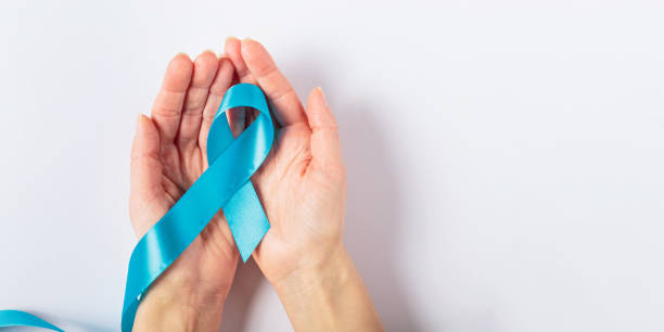 istock Blue cancer ribbon in woman's hand on white background 2194342491