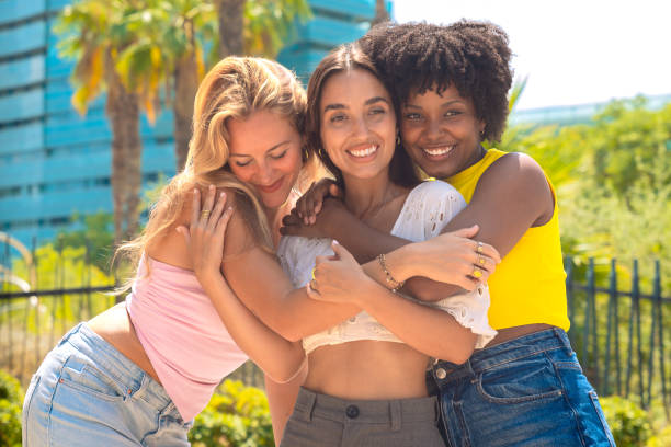 istock Three young women embracing and smiling outdoors on a sunny day 2194344521