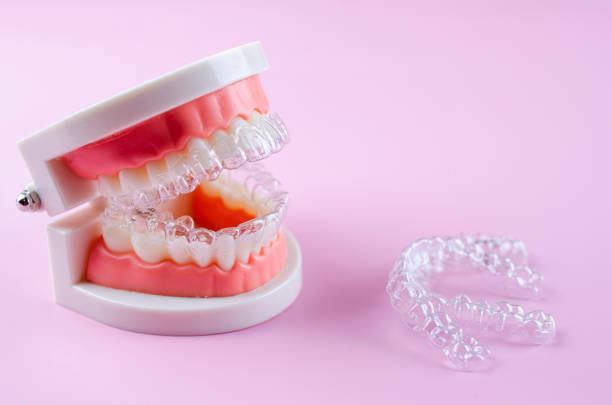 istock Close-up. Transparent aligners for artificial jaw teeth on a pink background 2194348244