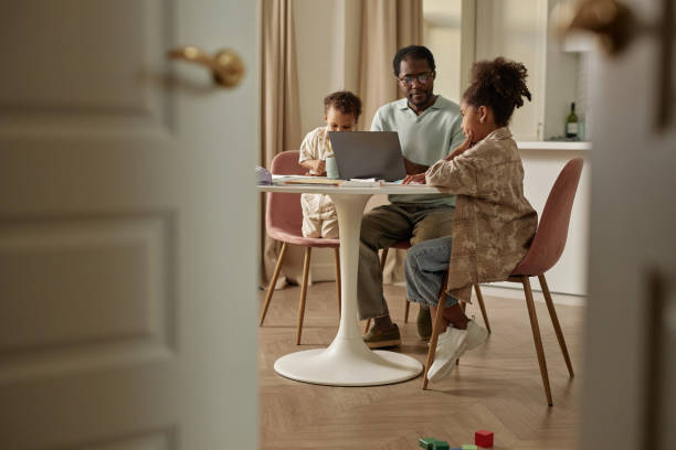 istock Black Girl Thinking over Task while Father Helping with Homework at Table in Living Room 2194353333