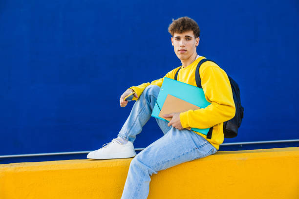 istock Young college student sitting and holding folders and smartphone 2194354971