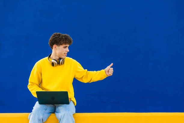 istock Young college student using laptop showing thumbs up sign 2194354990