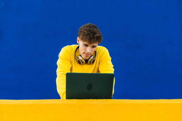 istock Young college student working on laptop with headphones 2194355013