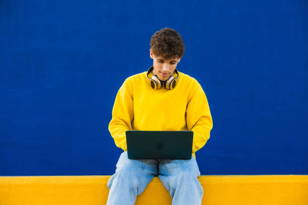 istock Young college student working on laptop with headphones 2194355035