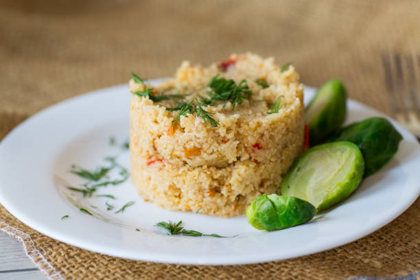homemade cooked bulgur with Brussel sprouts in a plate, on a wooden table .
