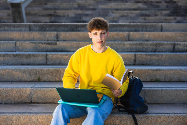 istock College student studying on laptop and book outdoors 2194355546