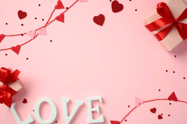istock Valentine's Day pink background with red and pink heart decorations, two gift boxes with red ribbons, and the word 