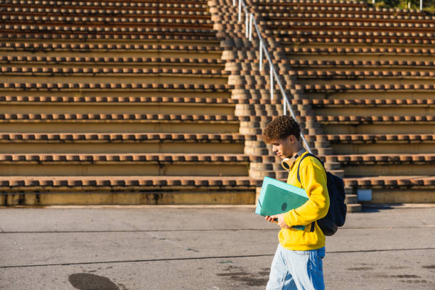 istock College student walking near bleachers carrying laptop and backpack 2194355708