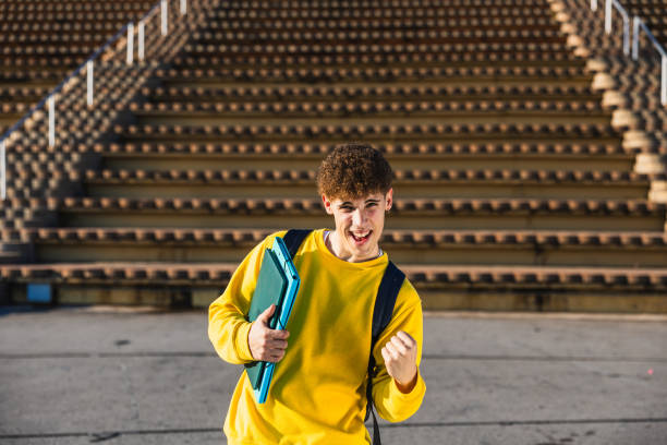 istock Excited college student celebrating success with laptop and backpack 2194355752