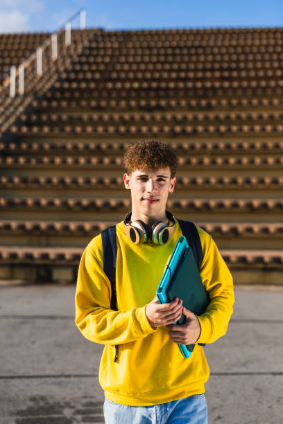 istock Young college student holding laptop and walking on campus 2194356240
