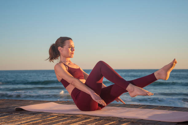 istock sporty woman doing boat pose outdoors by the ocean, core muscle workout 2194356244