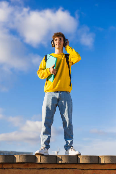istock Young student listening to music on rooftop with blue sky 2194356486