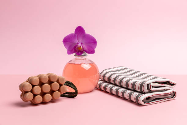 Personal hygiene products. Soap, a bottle of shower gel with an orchid flower and a towel on the pink background. Spa and wellness set.