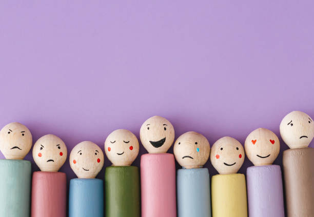 Image of different emotions on wooden peg dolls on purple background with copy space. Flat lay, top of view.
