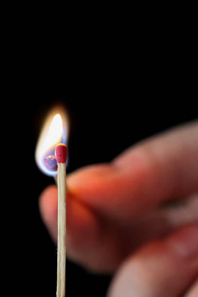 istock hand holding a lit matchstick with a bright flame against a black background, capturing the moment of ignition and the contrast of light and dark 2194365859