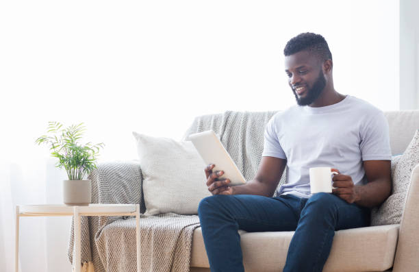 istock Man Enjoying Coffee While Reading on Tablet in Cozy Living Room 2194366712