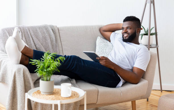 istock Relaxed Man Enjoying Leisure Time on a Cozy Sofa While Reading With a Tablet 2194366770