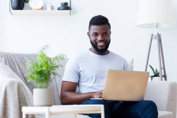 istock Man Working on Laptop at Home in Cozy Living Room While Smiling and Enjoying Remote Work Experience 2194366819