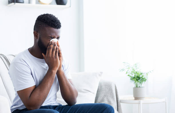 istock Man Sitting on Couch Feeling Emotional While Wiping Tears With Tissue in Bright Room 2194366842