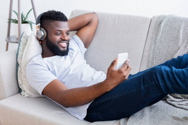 istock Relaxing Man Listens to Music While Using Smartphone on a Cozy Couch at Home 2194366876