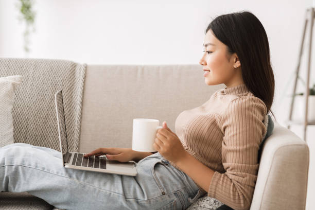 istock Young Woman Enjoying Coffee While Working on Laptop in Cozy Living Room Setting 2194366965