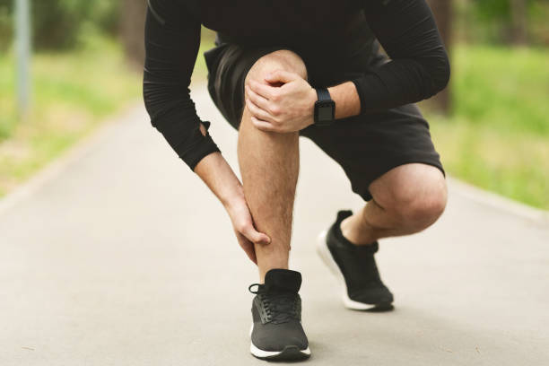 Runner Experiencing Leg Pain During Outdoor Exercise in a Park Setting