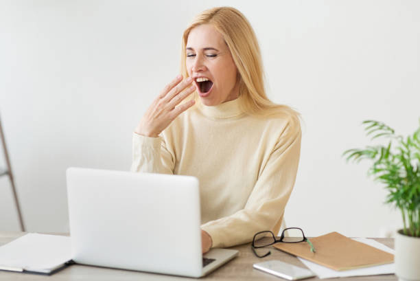 istock Woman Yawning While Working on Laptop in Modern Office Space During Daytime 2194368687