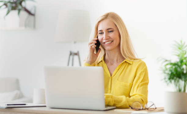 istock Smiling Woman Engages in Conversation While Working on Laptop at Home Office 2194368695