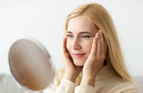 istock Mature Woman Looking At Mirror And Touching Face 2194368831