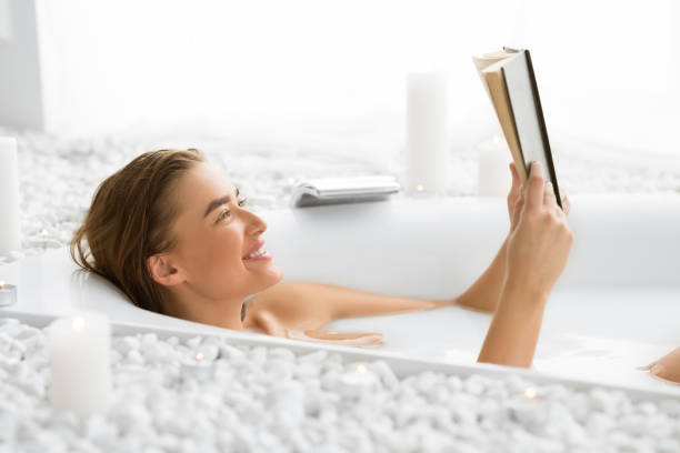 istock Happy woman reading book, lying in bath 2194369178
