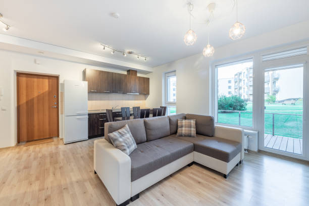 istock Modern Home Open Plan Kitchen and Living Room Interior with Dining Table and Window View. A well-lit modern apartment interior featuring an open-plan kitchen, dining area, and cozy living room 2194369268